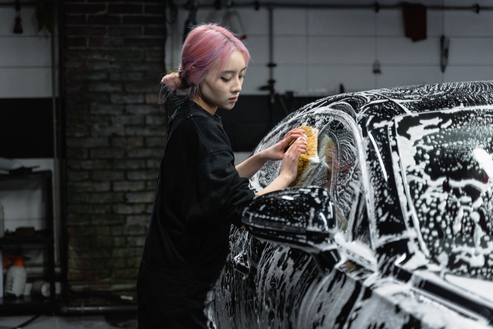 Hand-scrubbing a foam-covered luxury sedan