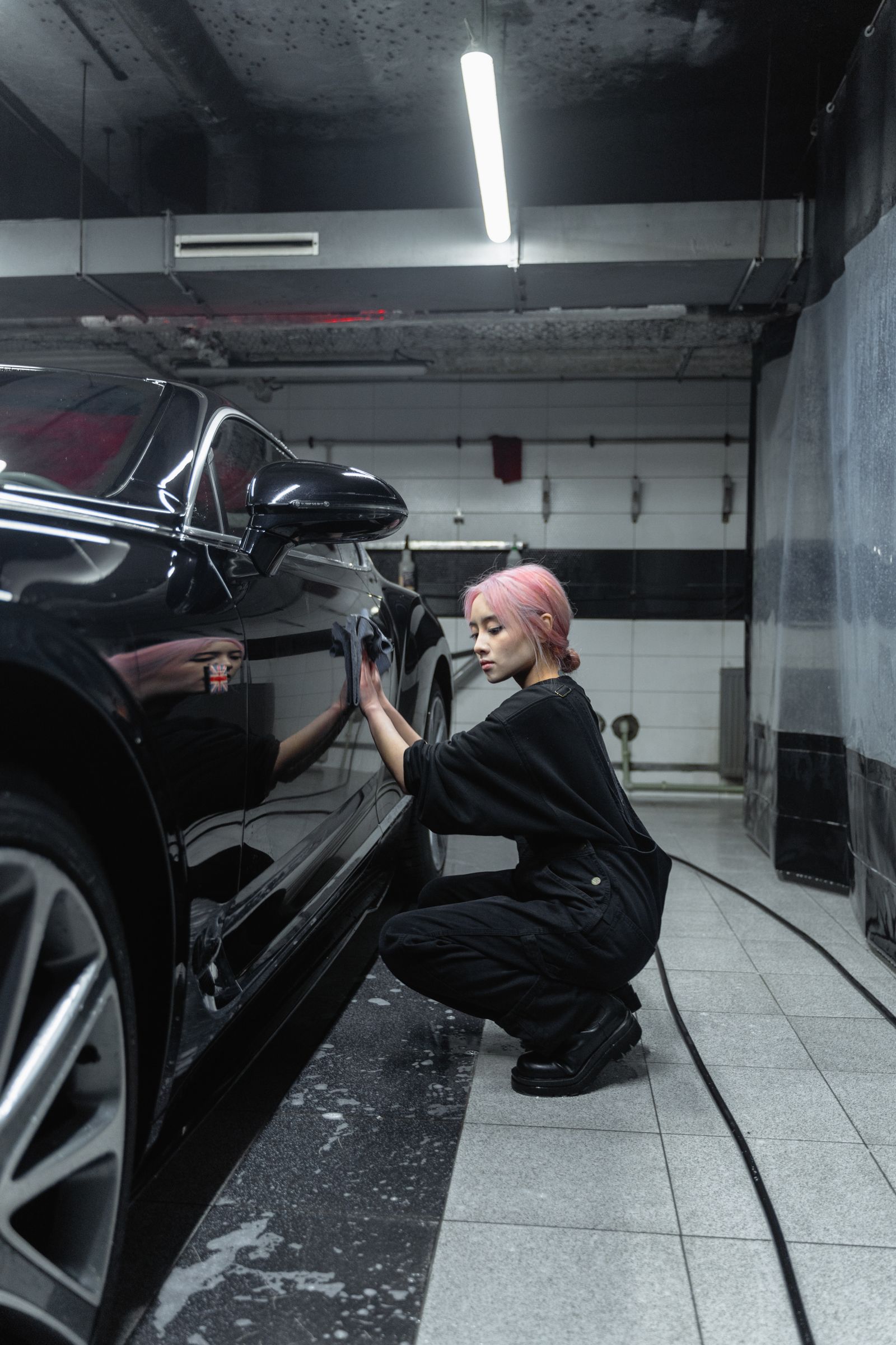 Detailer working the lower panels of a black sedan